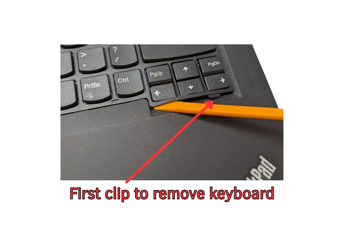 A laptop keyboard with a orange spudger under the keys.
